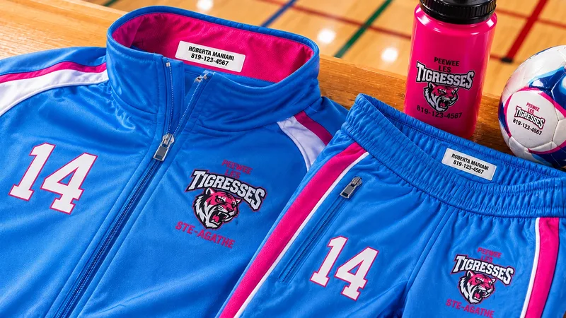 Ensemble de soccer bleu et rose de l'équipe Les Tigresses avec étiquettes de nom « Roberta Mariani — 819-123-4567 » au col, au short et sur la bouteille d'eau